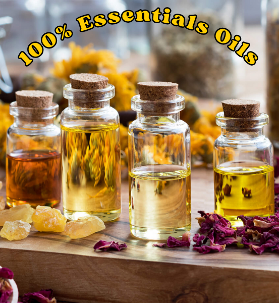 Four glass container bottles with cork lids containing essential oils on a wooden surface with flowers and herbs.