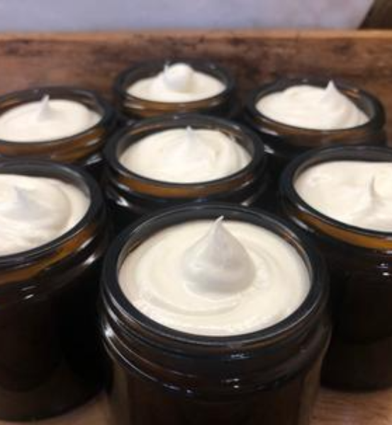 Image of seven dark brown jars containing white facial cream.